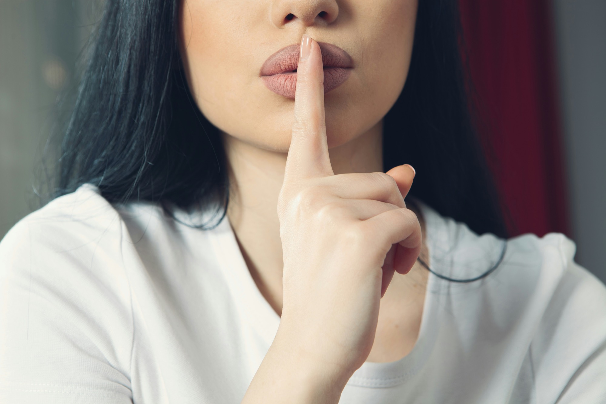 A woman holding a finger to her lips, asking for quiet.